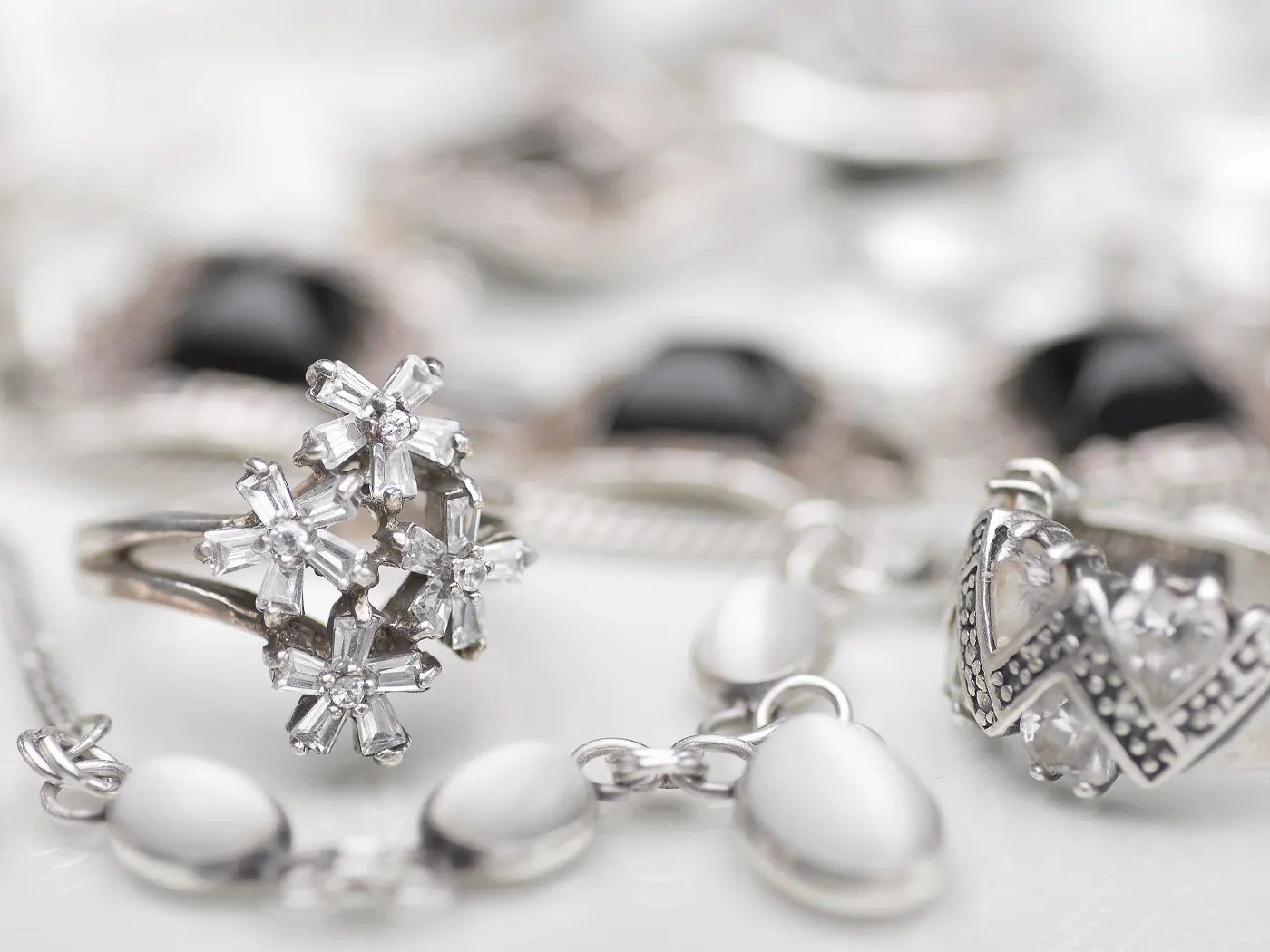 Elegant white gold jewelry featuring a floral ring and intricate designs, showcasing fine craftsmanship.