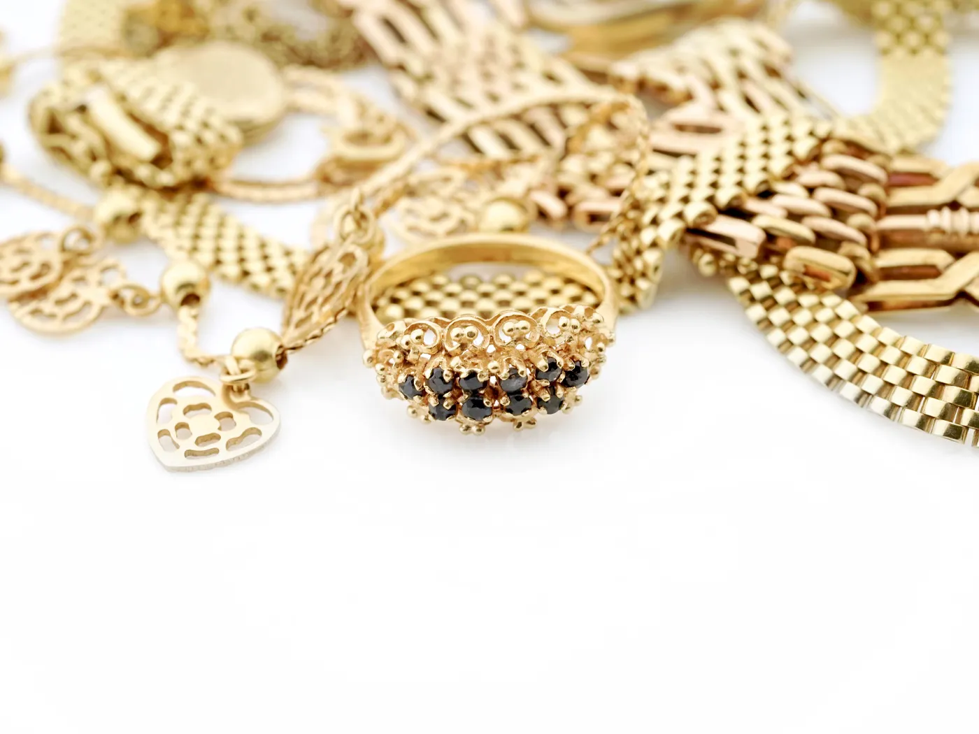 Gold jewelry featuring a decorative ring with black stones, surrounded by various gold chains.