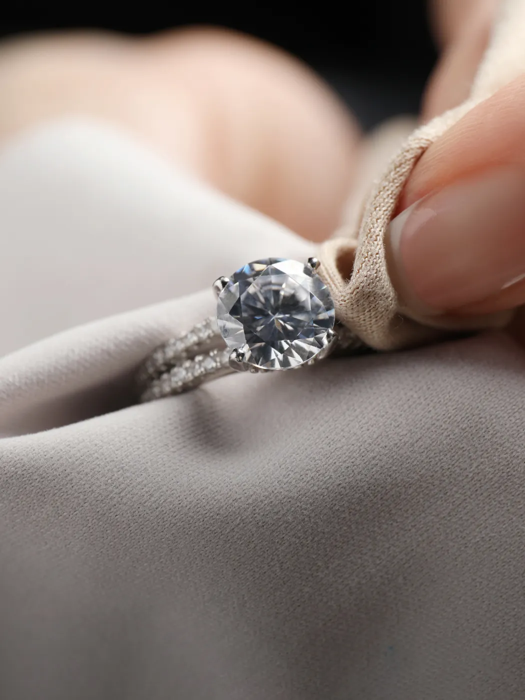 A hand polishing a diamond ring with a cloth.