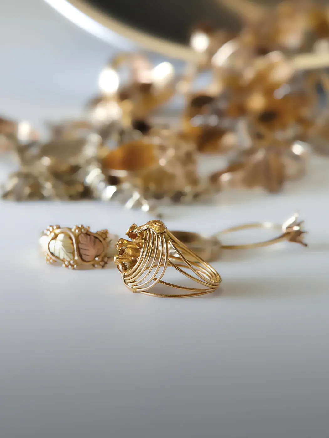 Gold rings on a white surface with blurred background of jewelry.