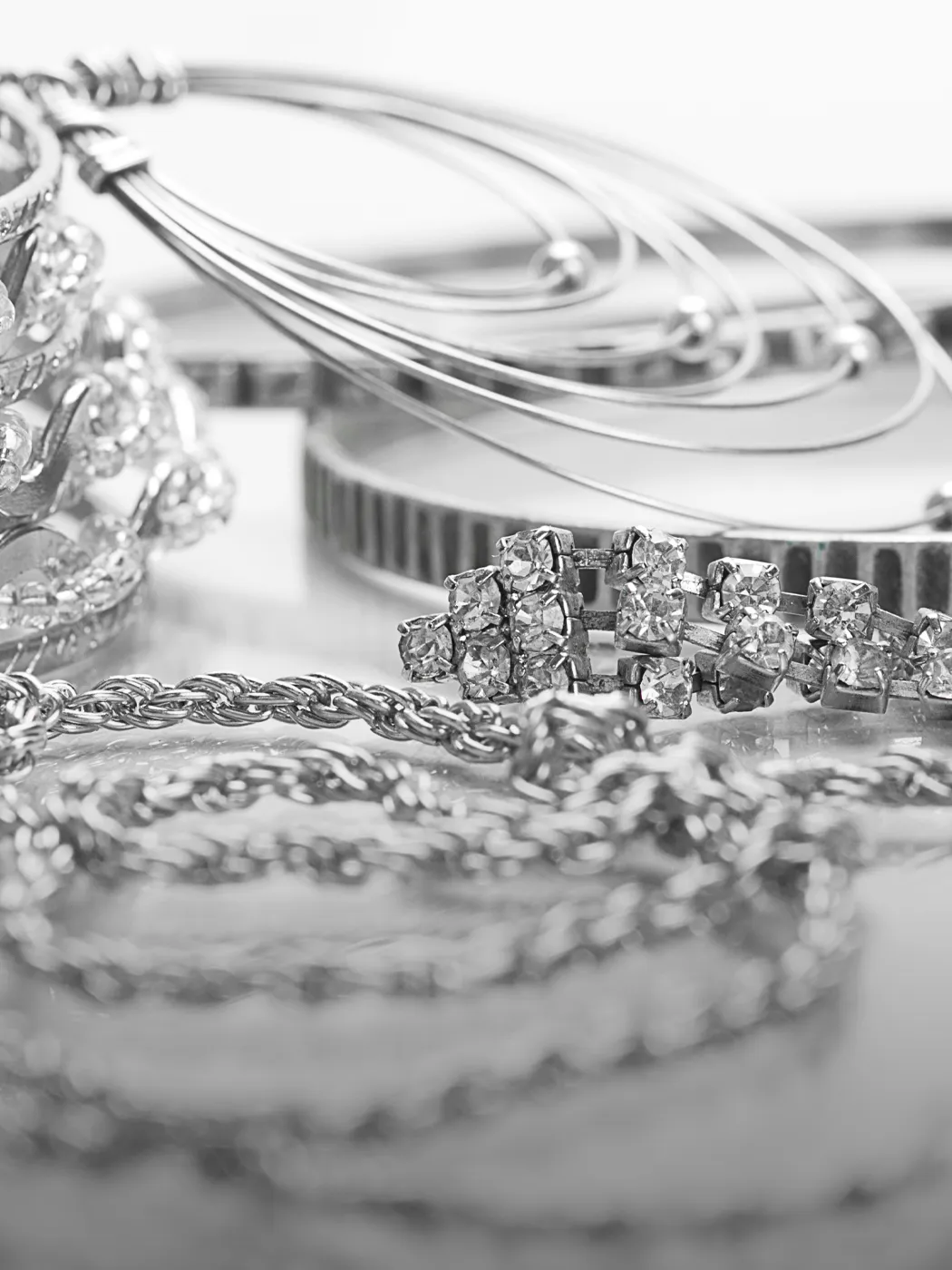 Close-up of silver jewelry, including rings, earrings, and a bracelet, showcasing rhodium plating.