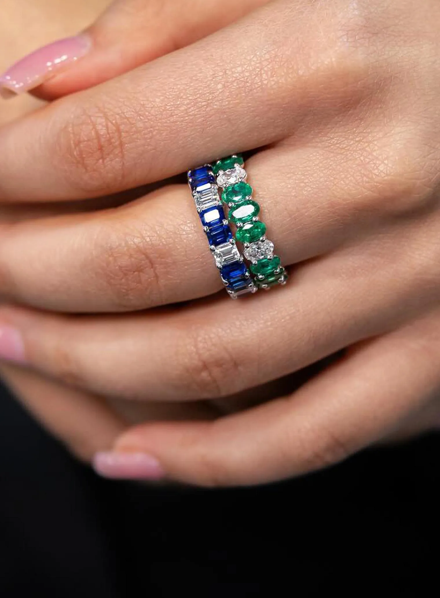 A silver ring with a large purple gemstone and two triangular side stones on a dark surface.