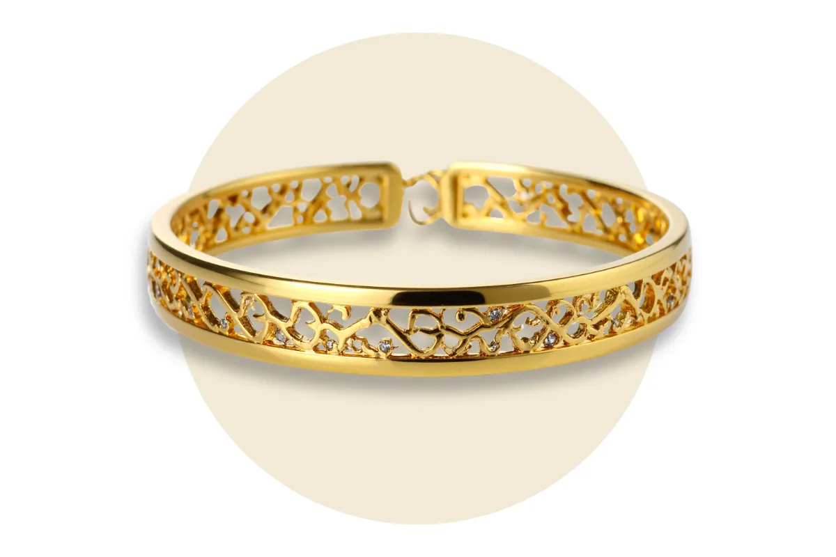 Elegant vintage gold bracelet with intricate cut-out design on a neutral background.