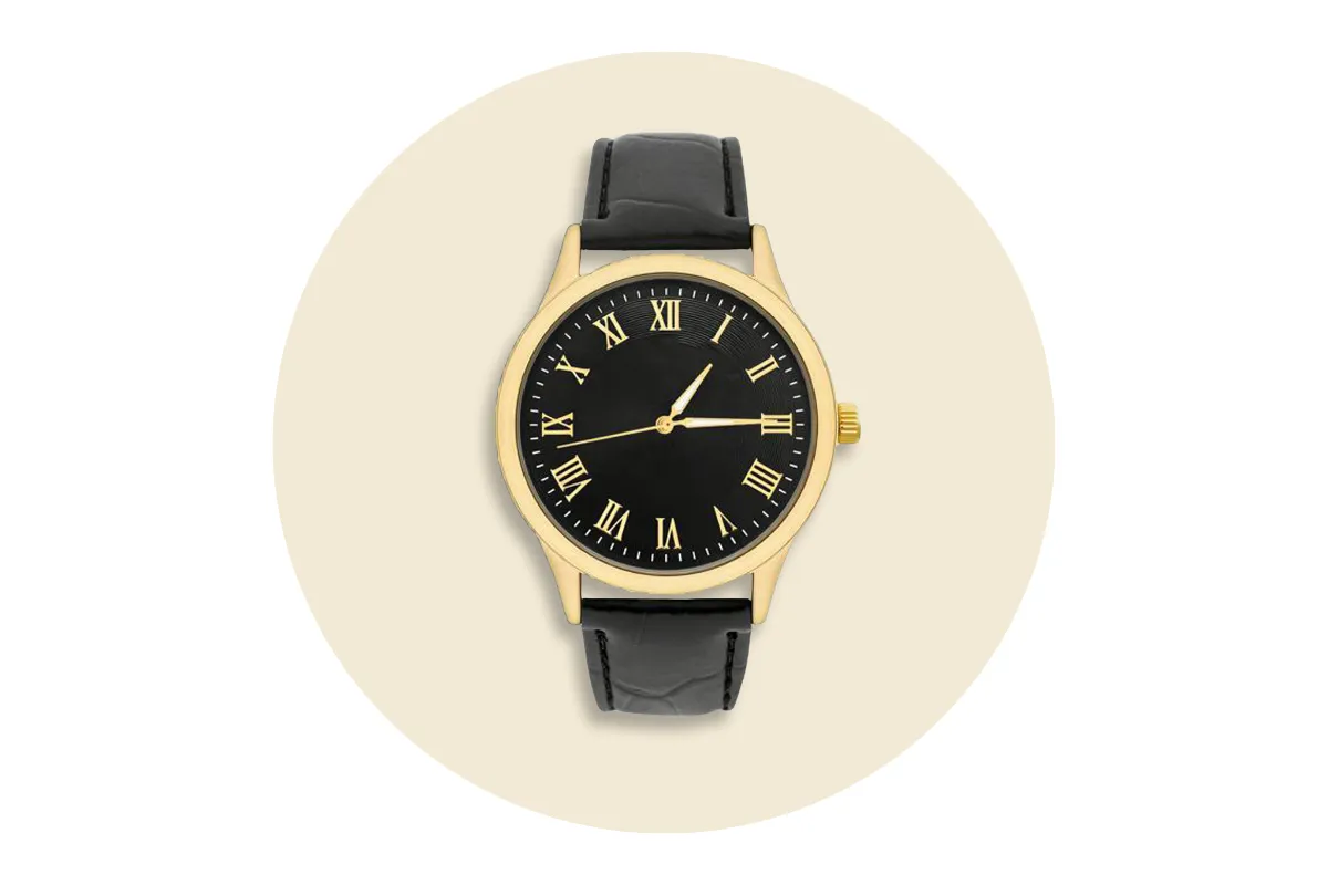 Vintage gold watch with black Roman numeral dial and black leather strap on beige background.