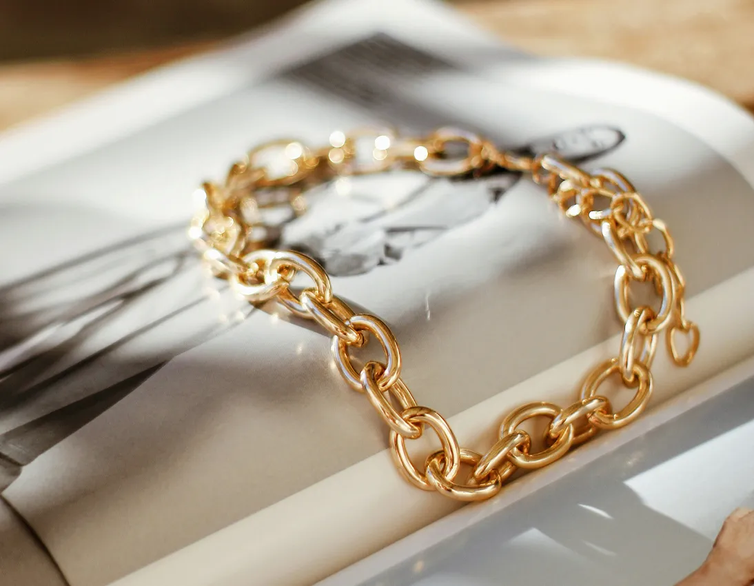 Gold chain bracelet resting on a magazine page, showcasing elegant jewelry design.