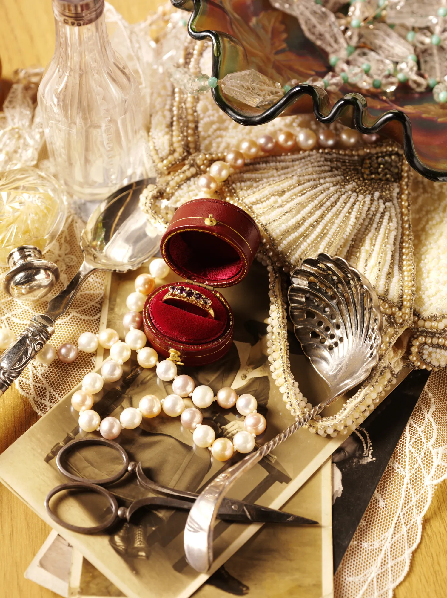 Vintage jewelry and accessories, including pearls and a ring in a red box, displayed on a table.