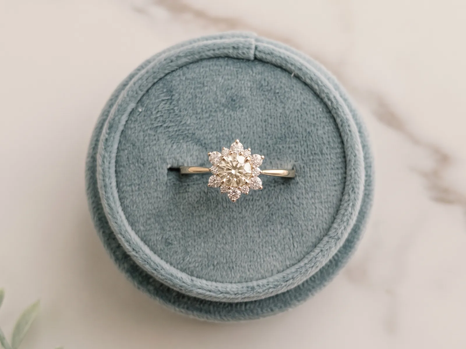 A diamond ring with a floral design on a blue velvet cushion.