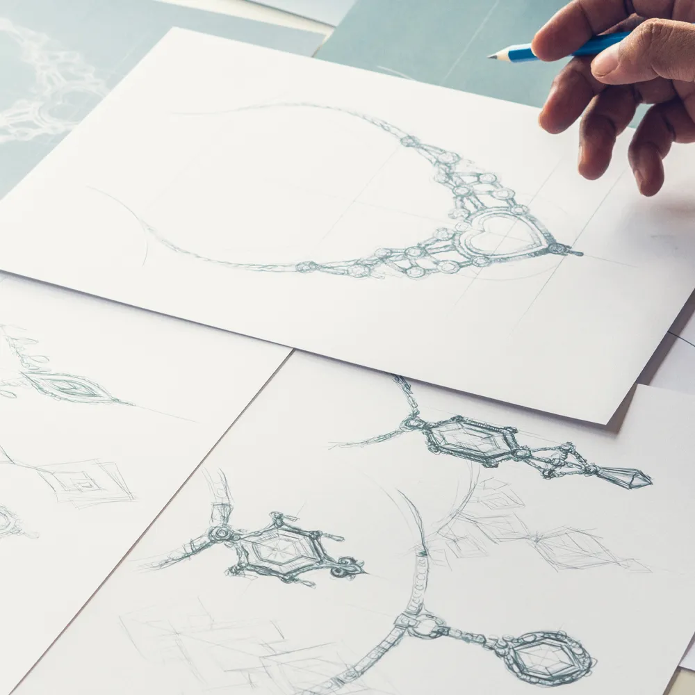 Hand sketching of intricate jewelry designs on paper, showcasing creativity and craftsmanship at Dream Jewelers.