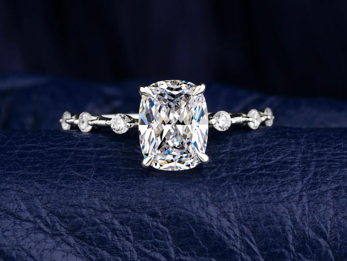 Elegant engagement ring with a large cushion-cut diamond and smaller accent diamonds on a silver band.
