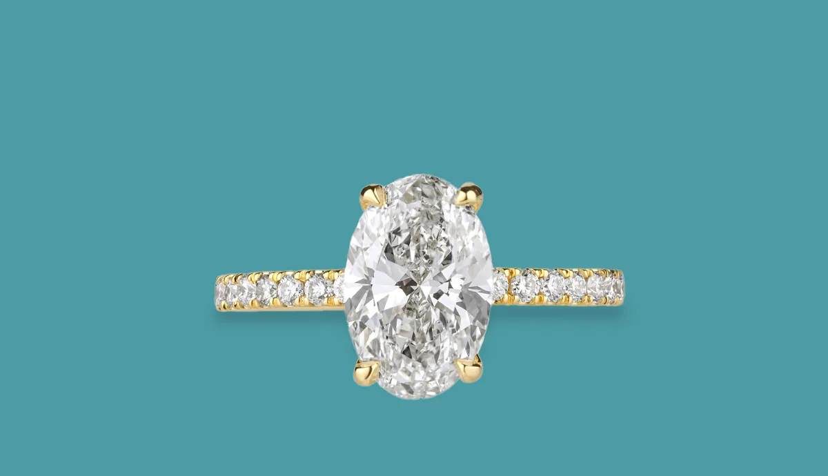 Elegant oval diamond engagement ring with a gold band and sparkling side stones, perfect for bridal jewelry.