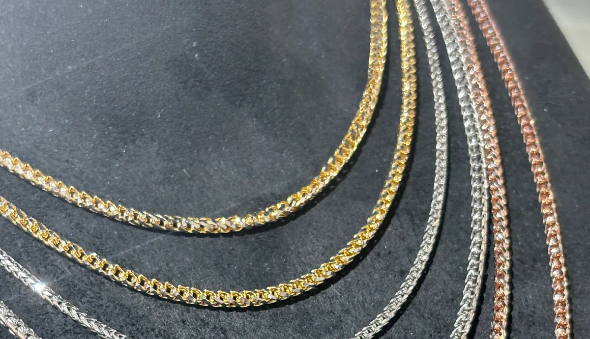 Gold and silver chains displayed on a black surface