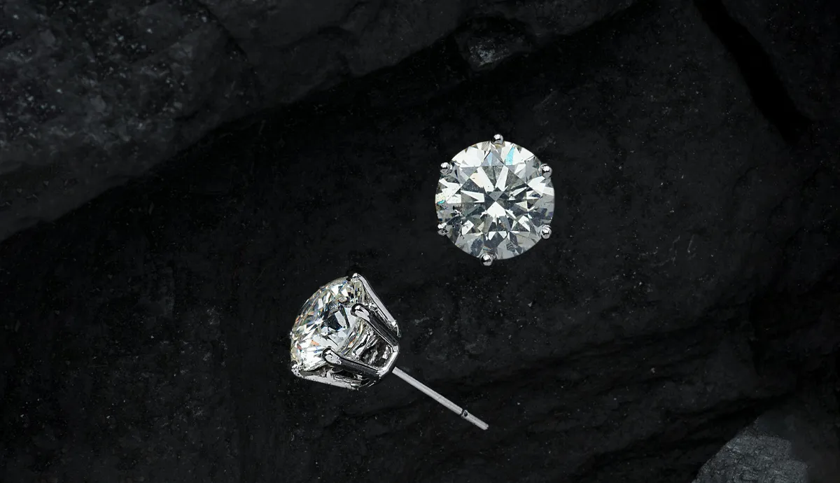 Two sparkling diamond earrings on a dark background, showcasing their brilliance and elegance.