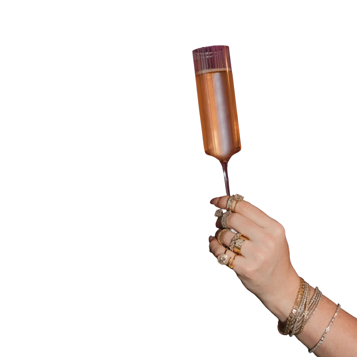 Woman holding champagne flute wearing bracelets and rings. 