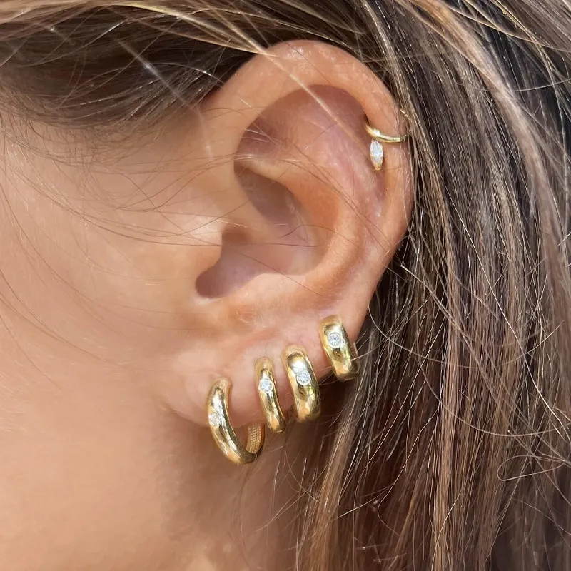 Gold hoop earrings with sparkling accents worn on a woman's ear.