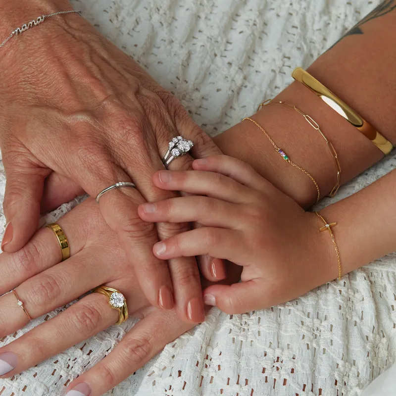 Three generations of hands adorned with rings and bracelets, symbolizing family connections and love.