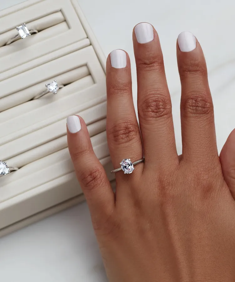 A hand with a diamond engagement ring, showcasing different ring options.