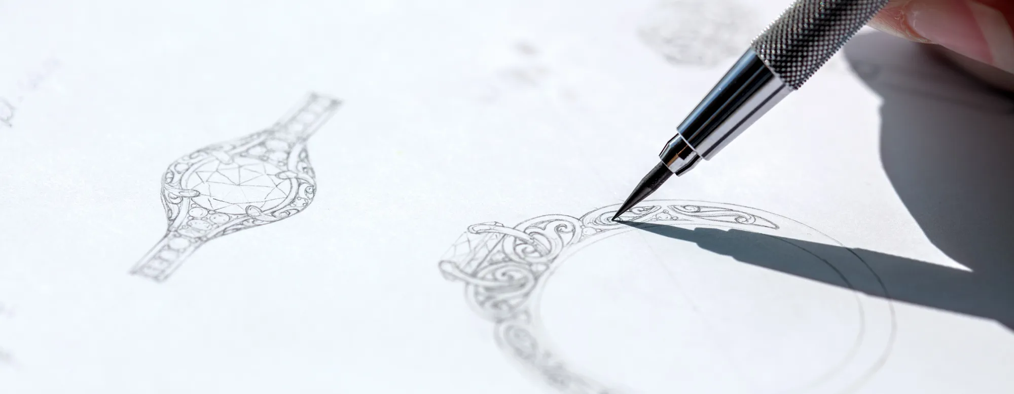 Sketch of an intricate jewelry design with a hand holding a pen, illustrating craftsmanship