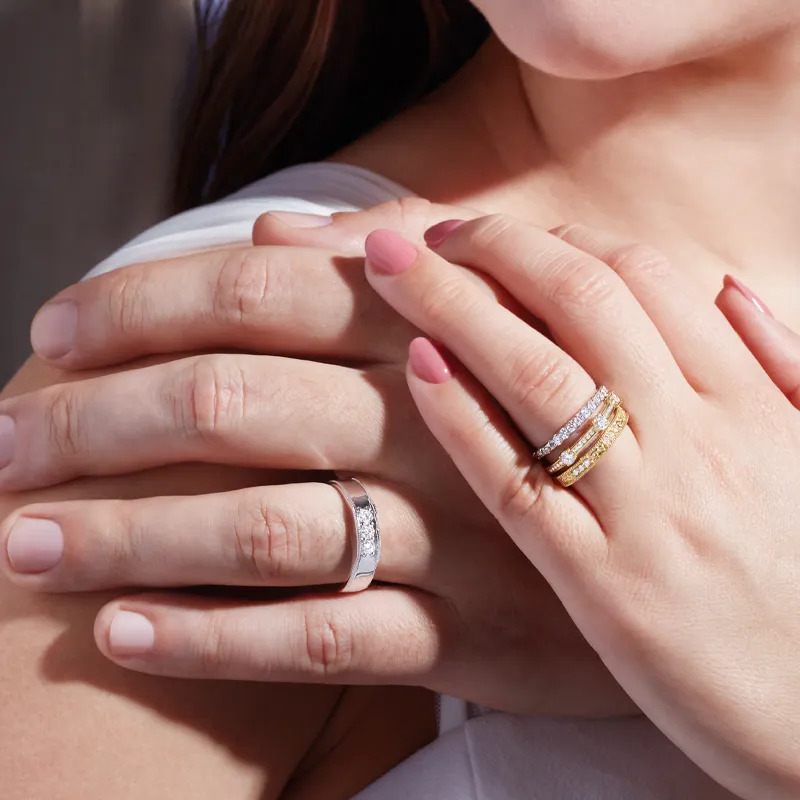 Close-up of a woman's hands showcasing multiple elegant rings, including a silver band and gold stackable bands.