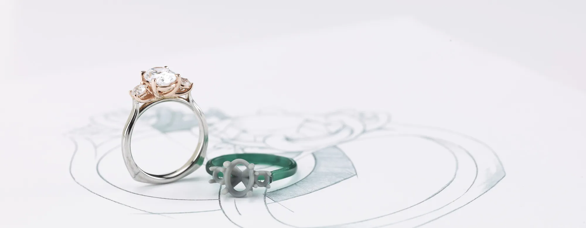 Handcrafted engagement ring with a diamond, alongside a design sketch and a wax model.
