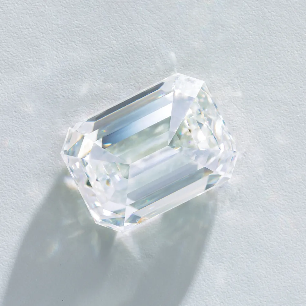 Clear emerald-cut diamond on a light background, showcasing its brilliance and clarity.
