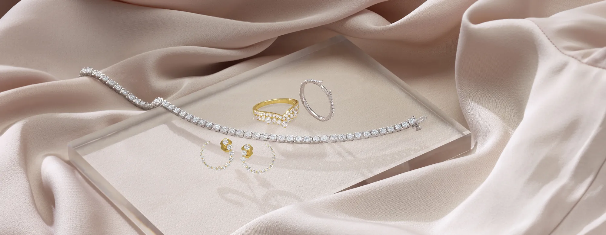 Elegant jewelry display featuring a diamond bracelet, earrings, and a ring on soft fabric.