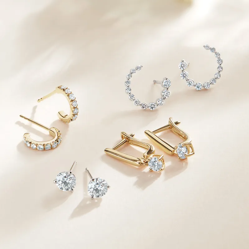 Elegant assortment of gold and silver earrings featuring sparkling stones, displayed on a soft background.