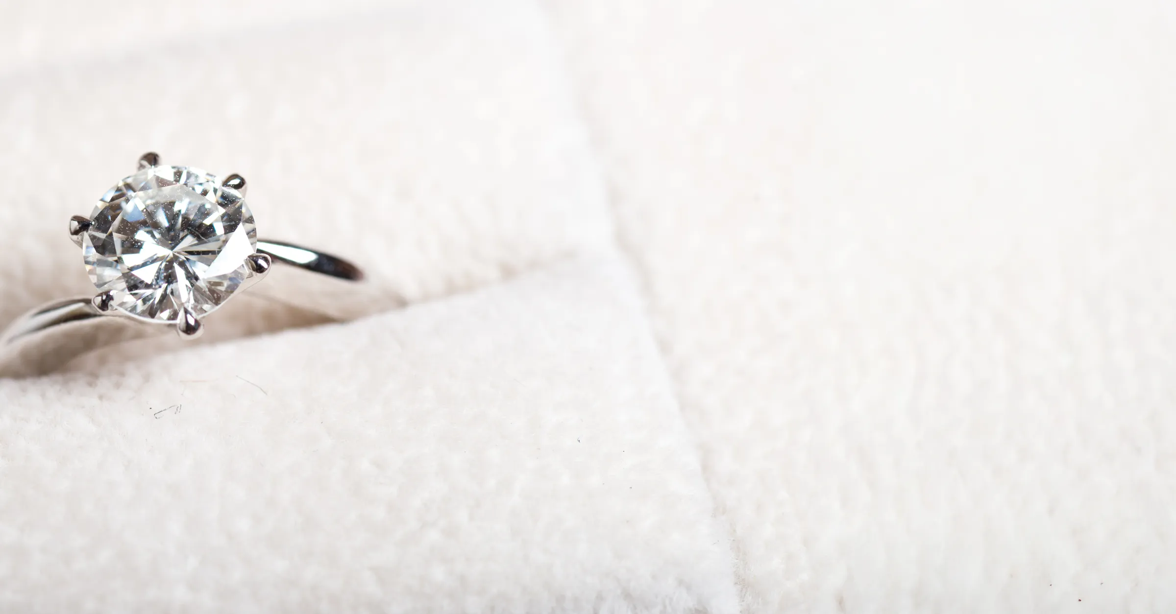 Engagement ring on a bride's hand, holding a bouquet of flowers. Click to read more testimonials from E.G. Landis Jewelers.