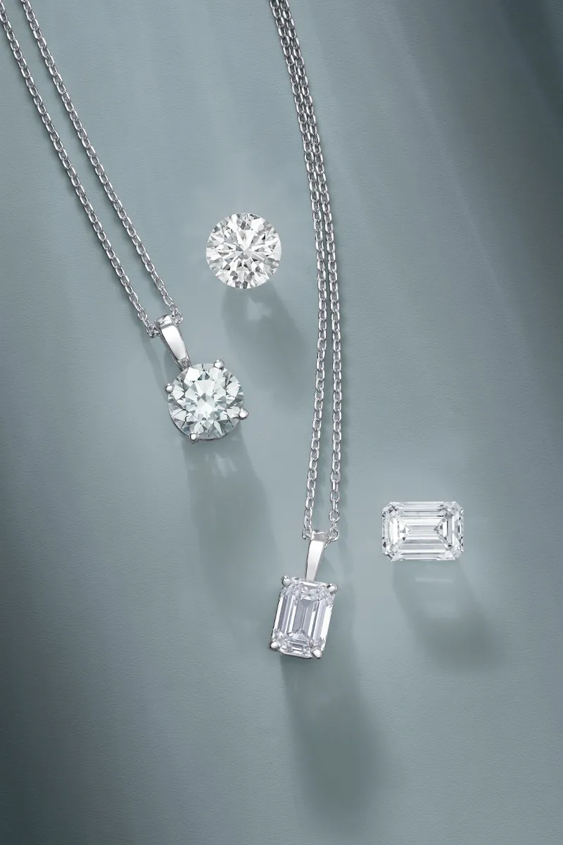 Elegant diamond jewelry including pendants and loose stones on a soft surface.