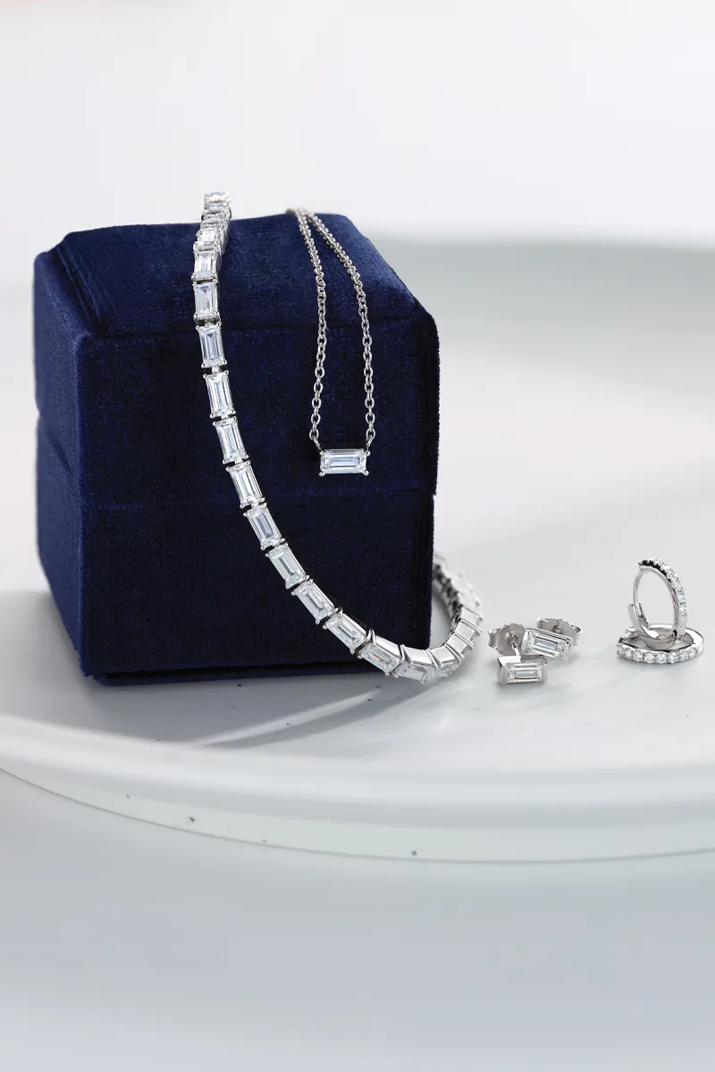 Elegant jewelry set including a necklace, earrings, and bracelet displayed on a blue velvet box.