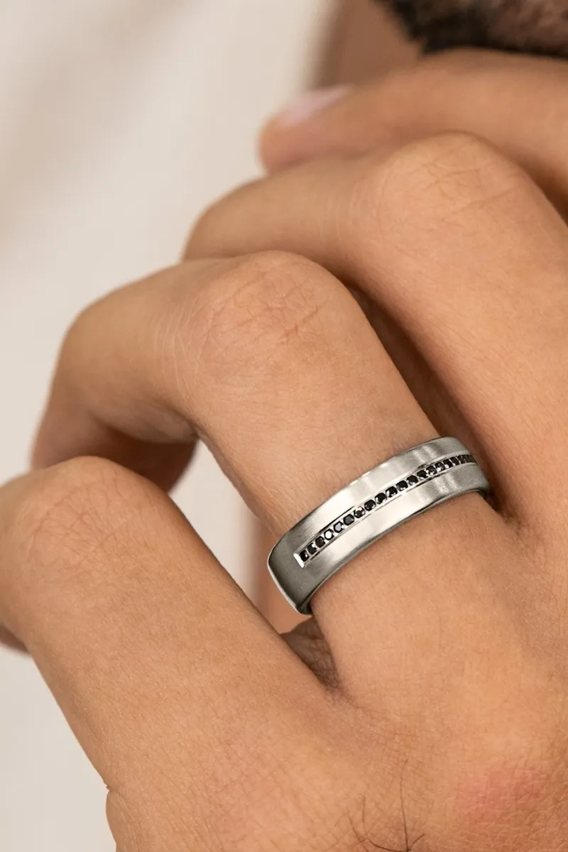 Stylish silver ring with a sleek design worn on a finger.