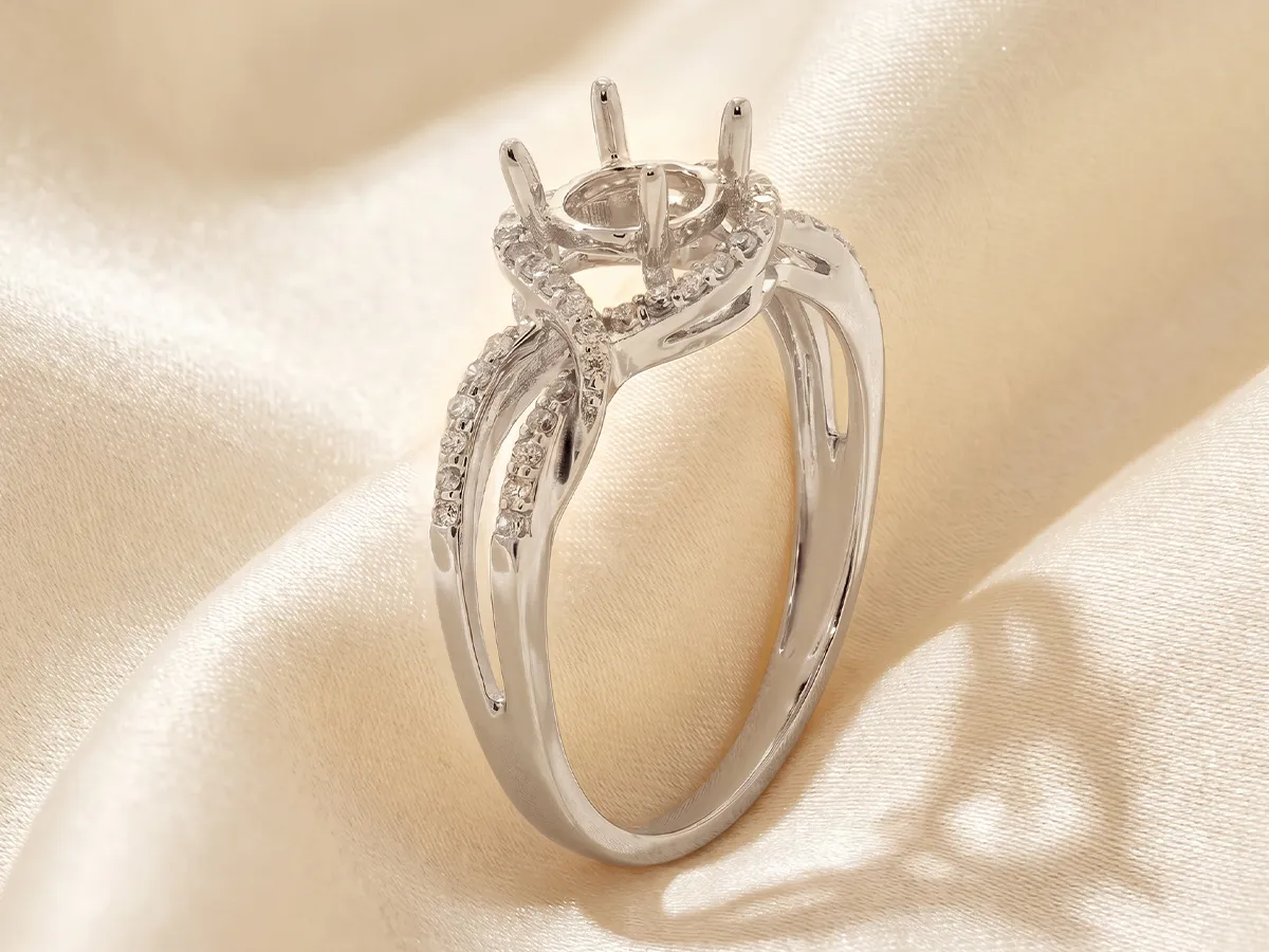 Silver engagement ring setting with diamond accents on a satin background. Click to learn more.