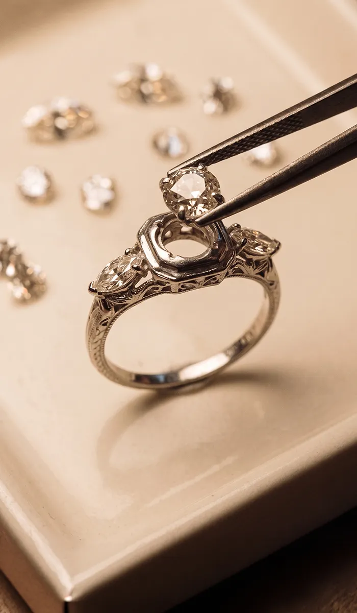 Jeweler setting a diamond in a ring with tweezers.