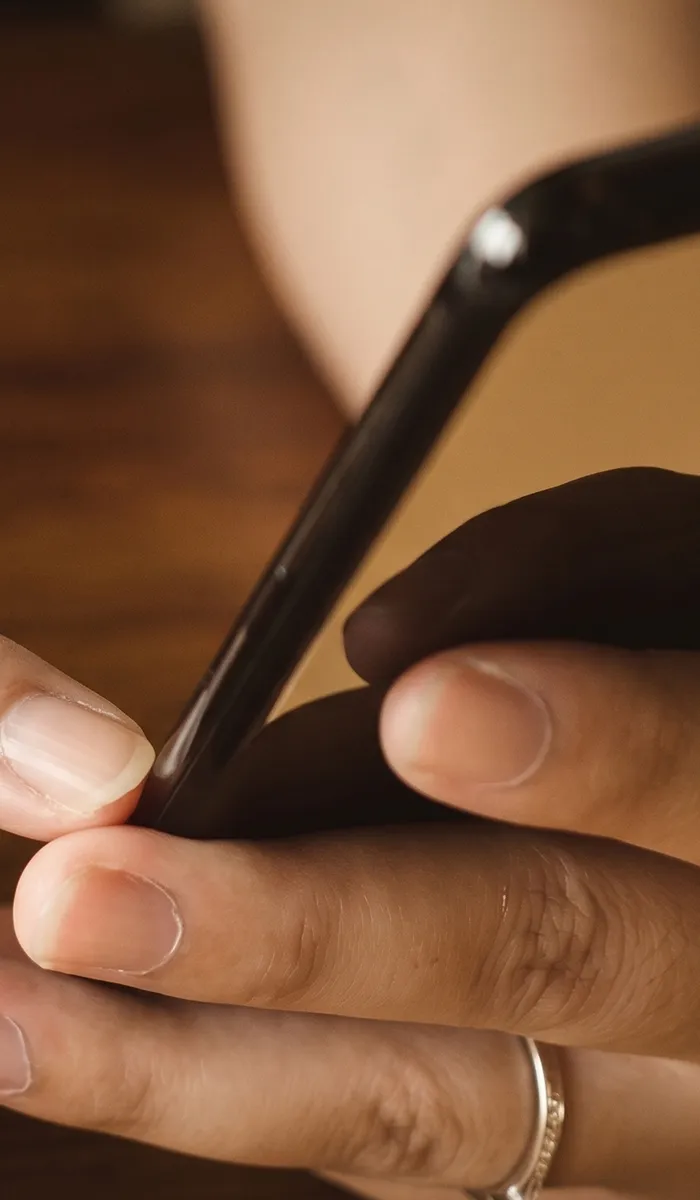 Hands holding a phone, one wearing a diamond ring. Click to browse Erley Diamonds' inventory.
