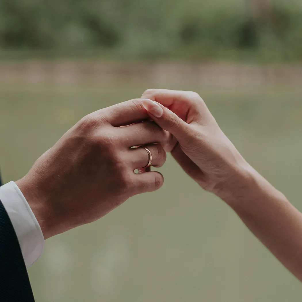 Close-up of a couple's hands with a wedding ring, symbolizing love and commitment. Visit Falls Jewelers for wedding bands.
