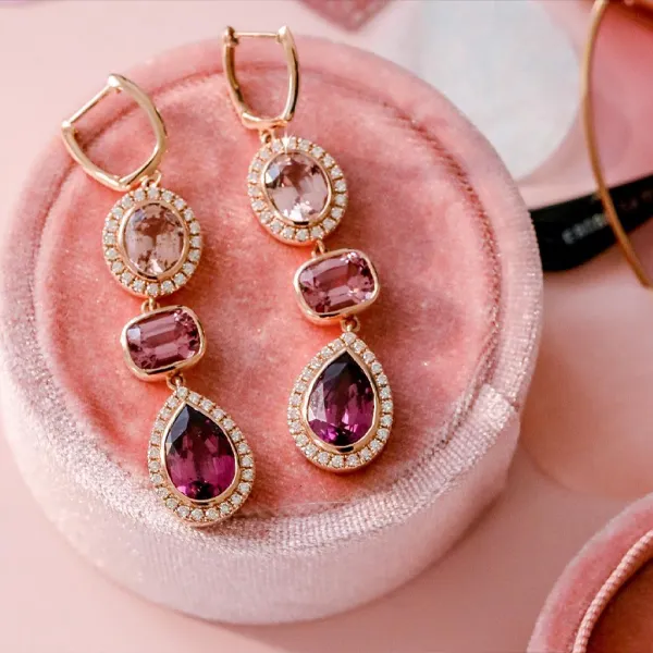 Elegant gold earrings with colored stones displayed on a pink velvet jewelry box. Shop colored stone jewelry at Falls Jewelers.