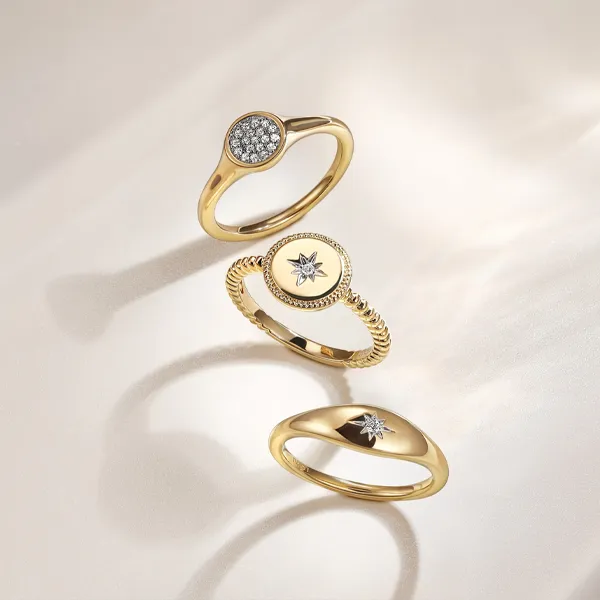 Three elegant gold rings featuring diamonds and star motifs, promoting gold jewelry at Falls Jewelers. Shop now!