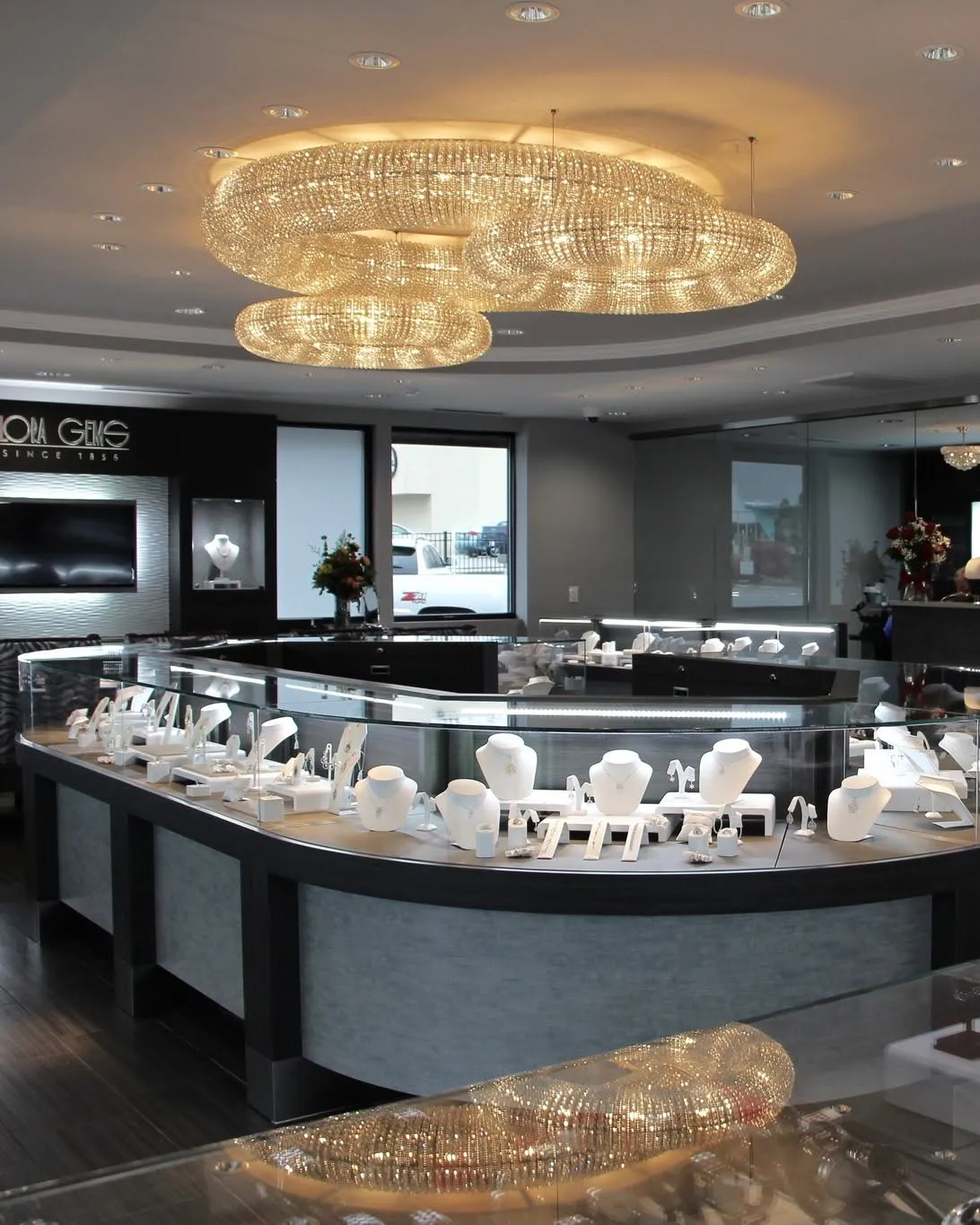 Luxurious jewelry store interior with elegant chandeliers and display cases showcasing various jewelry pieces.