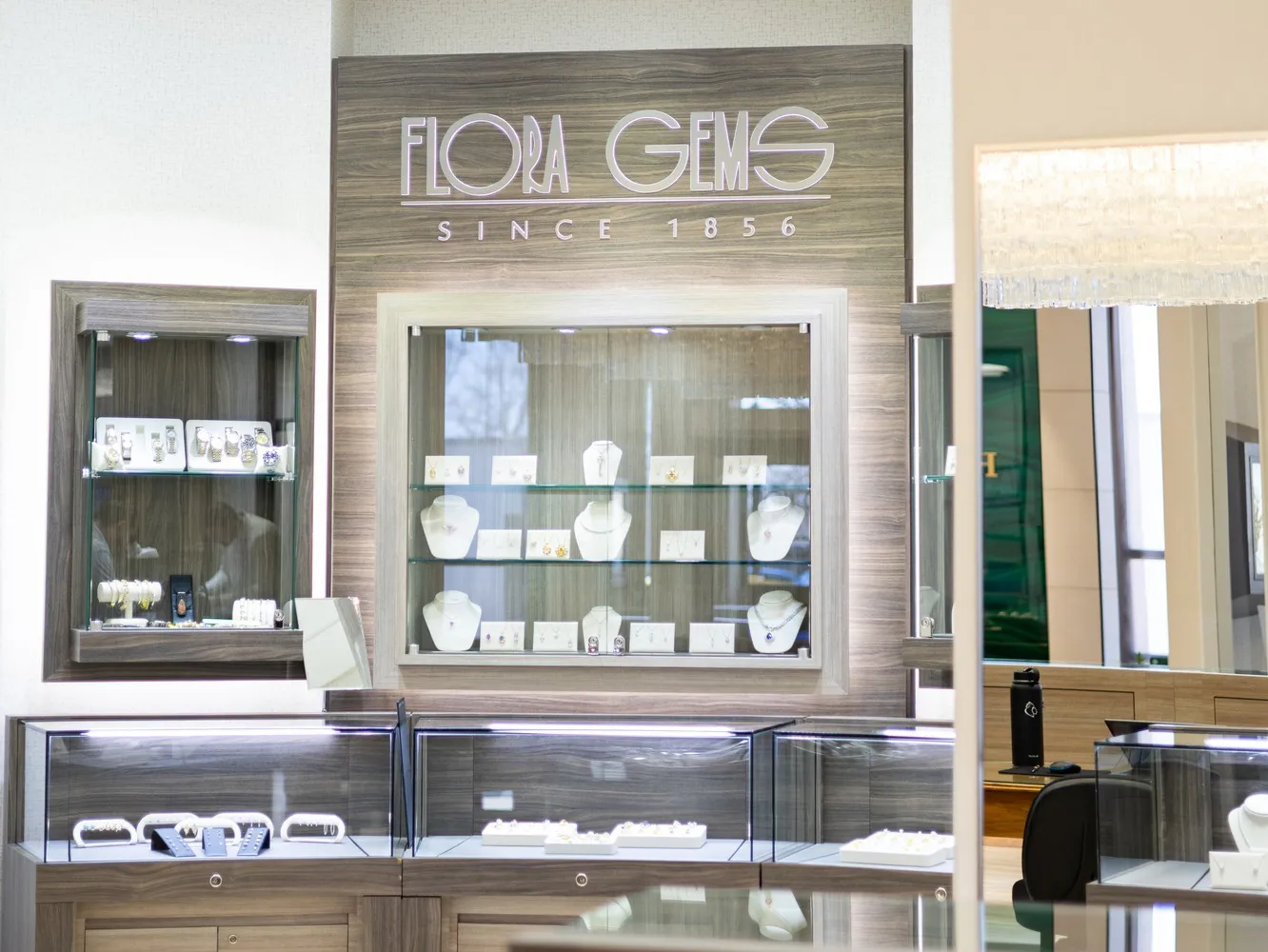 Flora Gems jewelry store display featuring elegant pieces and a sign indicating 