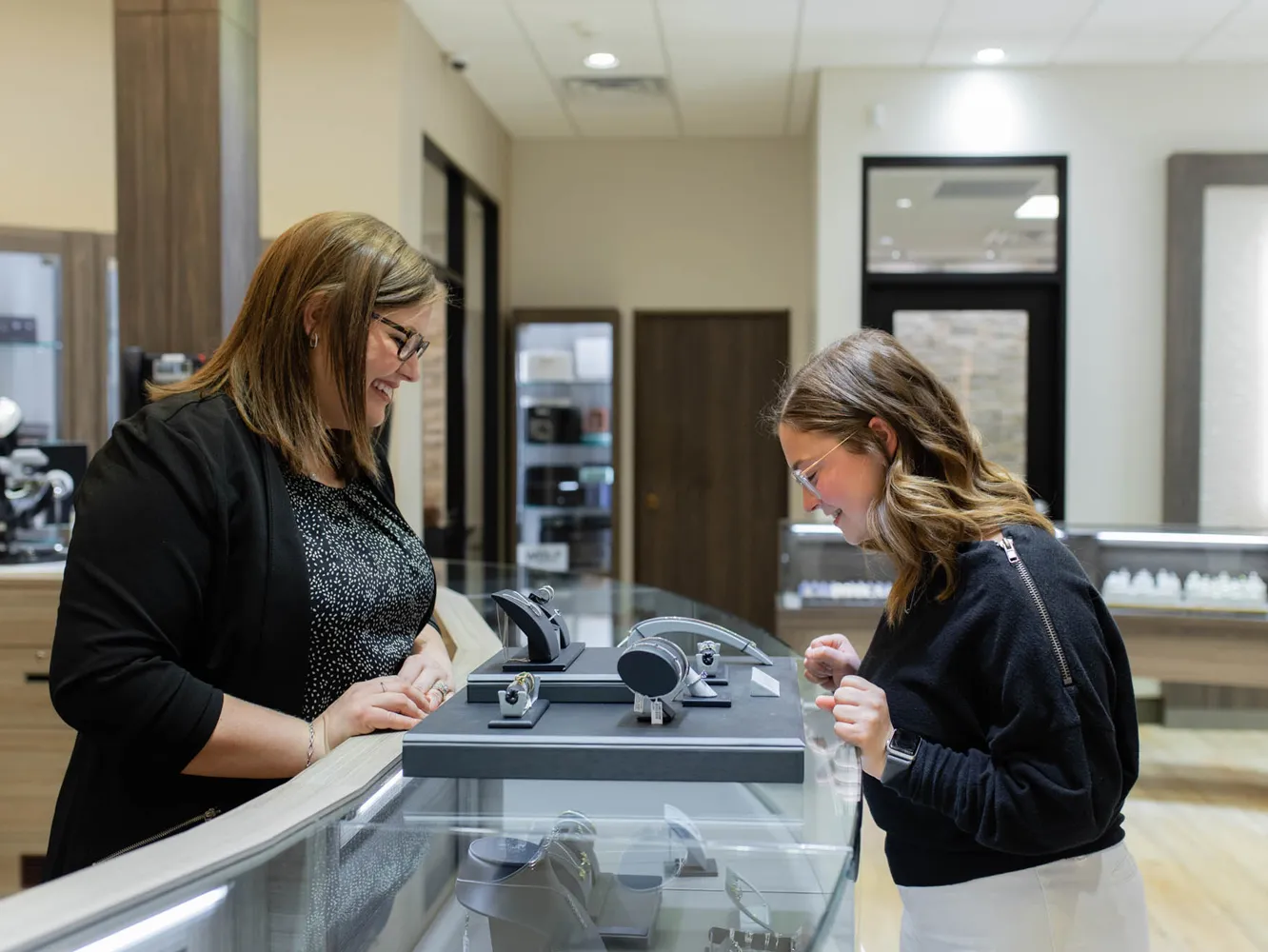 A customer admires jewelry with a sales associate in a bright jewelry store.