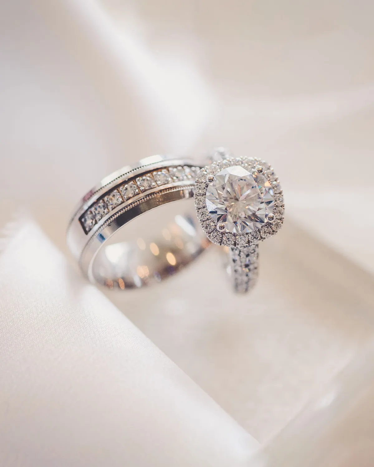 Elegant diamond engagement and wedding rings on soft fabric.