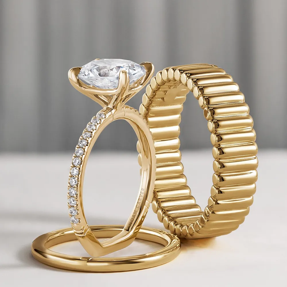 Gold engagement and wedding rings featuring a diamond centerpiece and a textured band, displayed elegantly.