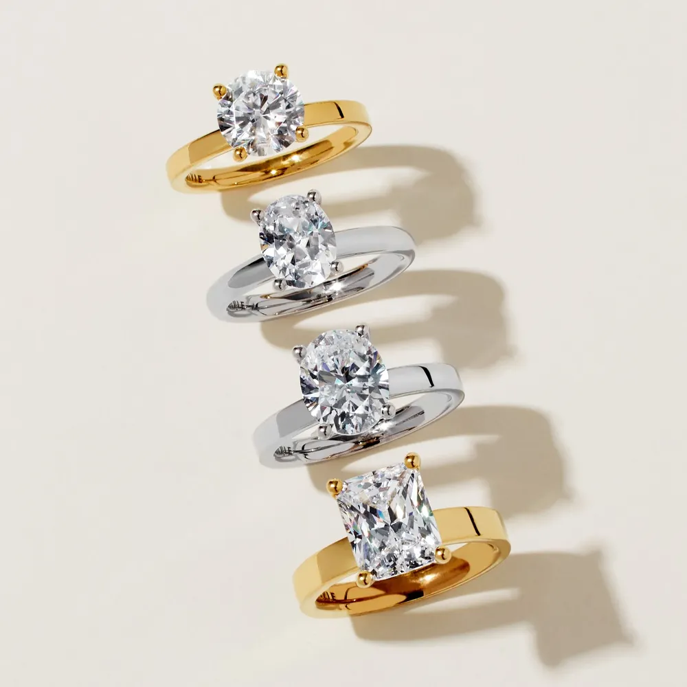 Four elegant rings featuring sparkling diamonds in gold and silver settings, showcasing various styles and shapes.
