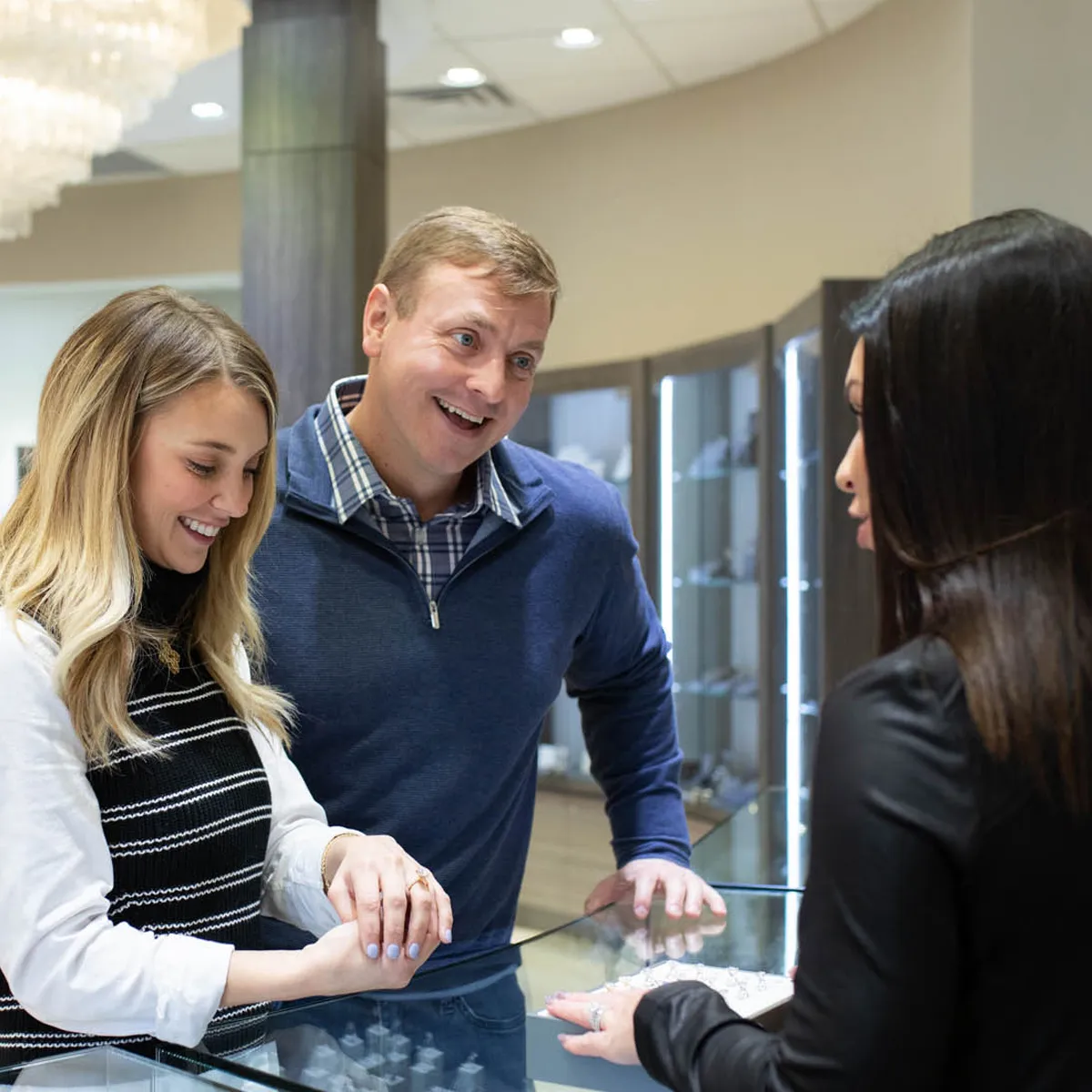 Couple joyfully consulting with a jeweler about a ring at Flora Gems jewelry store in Decatur, IL.