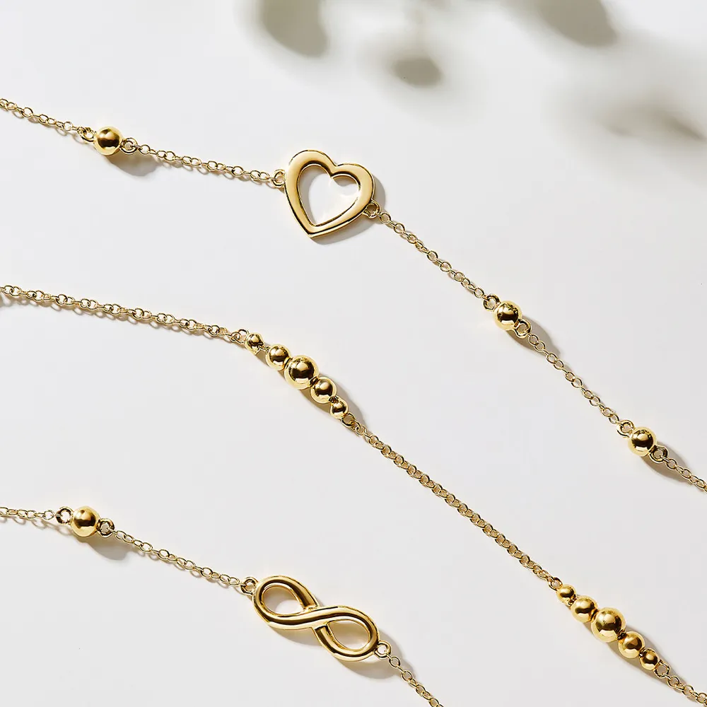 Gold bracelets featuring heart and infinity charms, perfect for gifting or personal style.