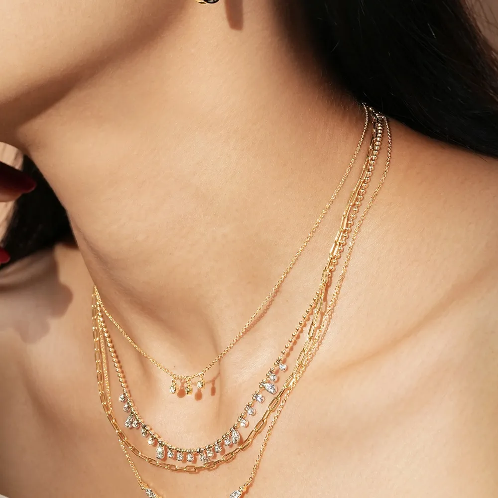 Close-up of layered gold chains and a delicate necklace on a model's neck.