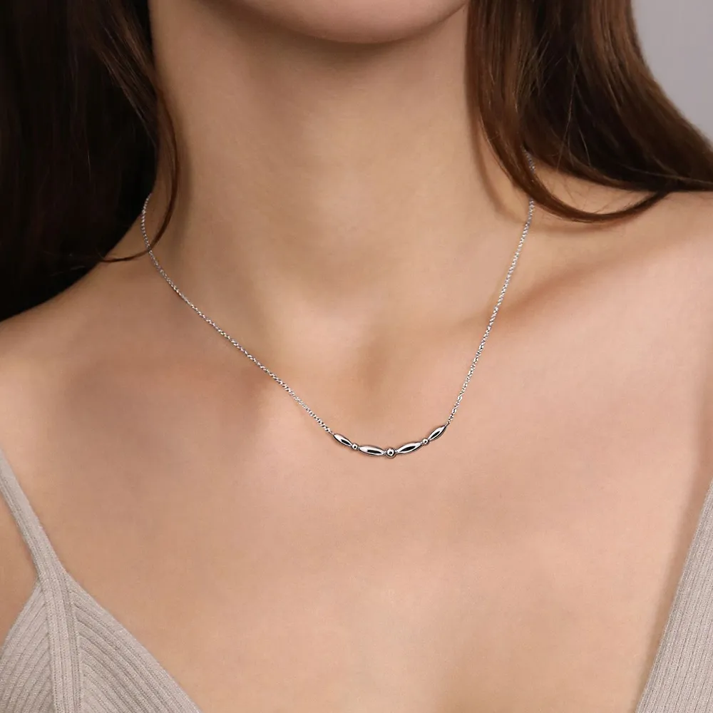 Silver necklace with a curved design worn by a model, showcasing elegance and style.