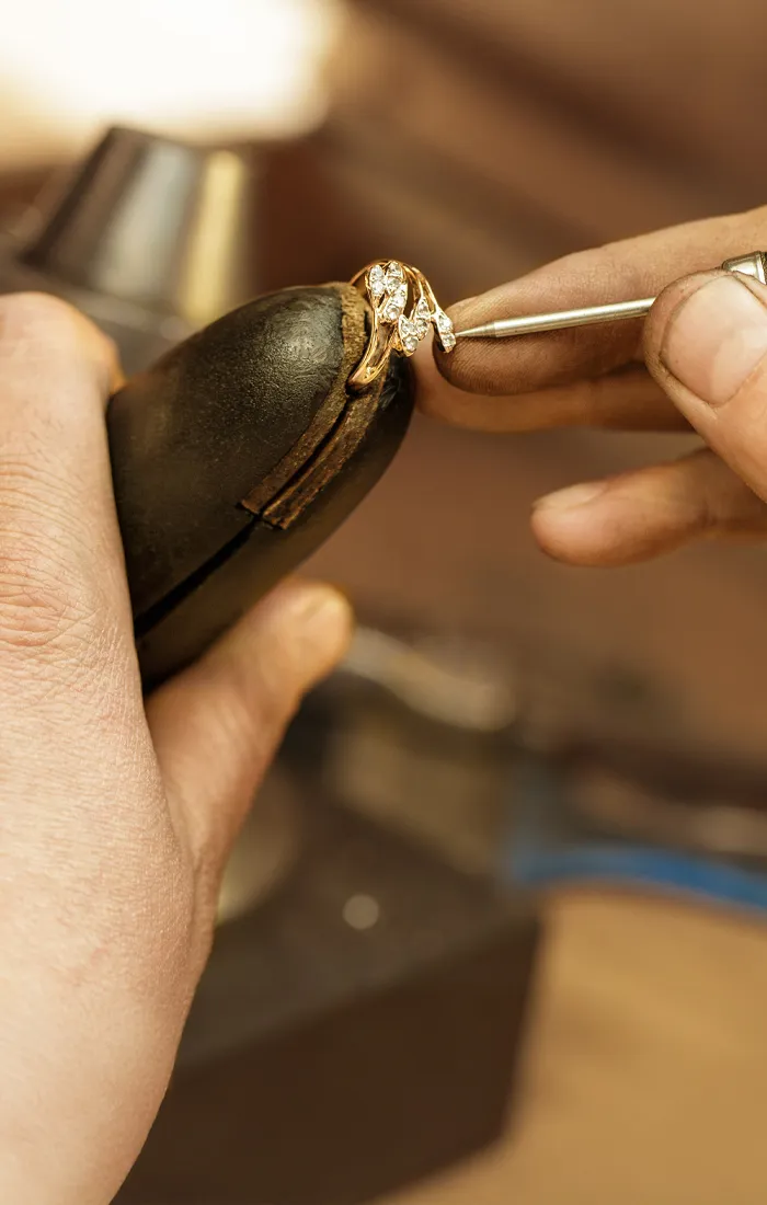 Jeweler restoring a vintage ring with diamonds, showcasing craftsmanship.