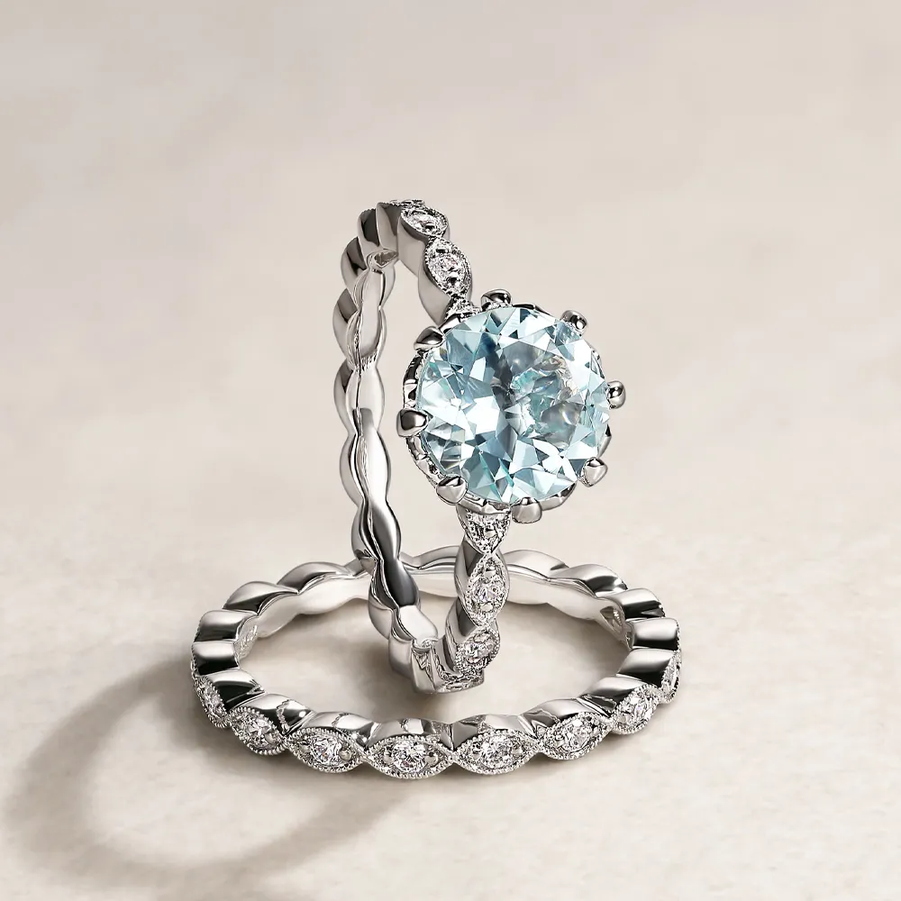 Aquamarine engagement ring set with a twisted band and diamond accents, displayed on a light surface.