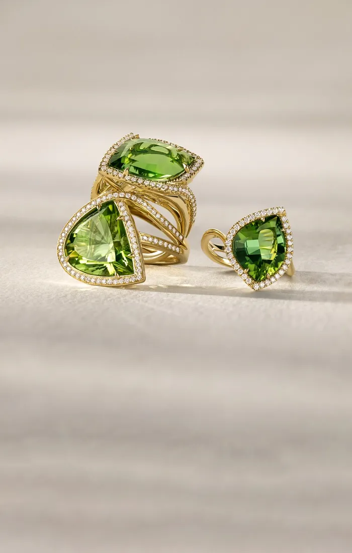 Three elegant gold rings featuring vibrant green gemstones, showcasing a luxurious jewelry collection.