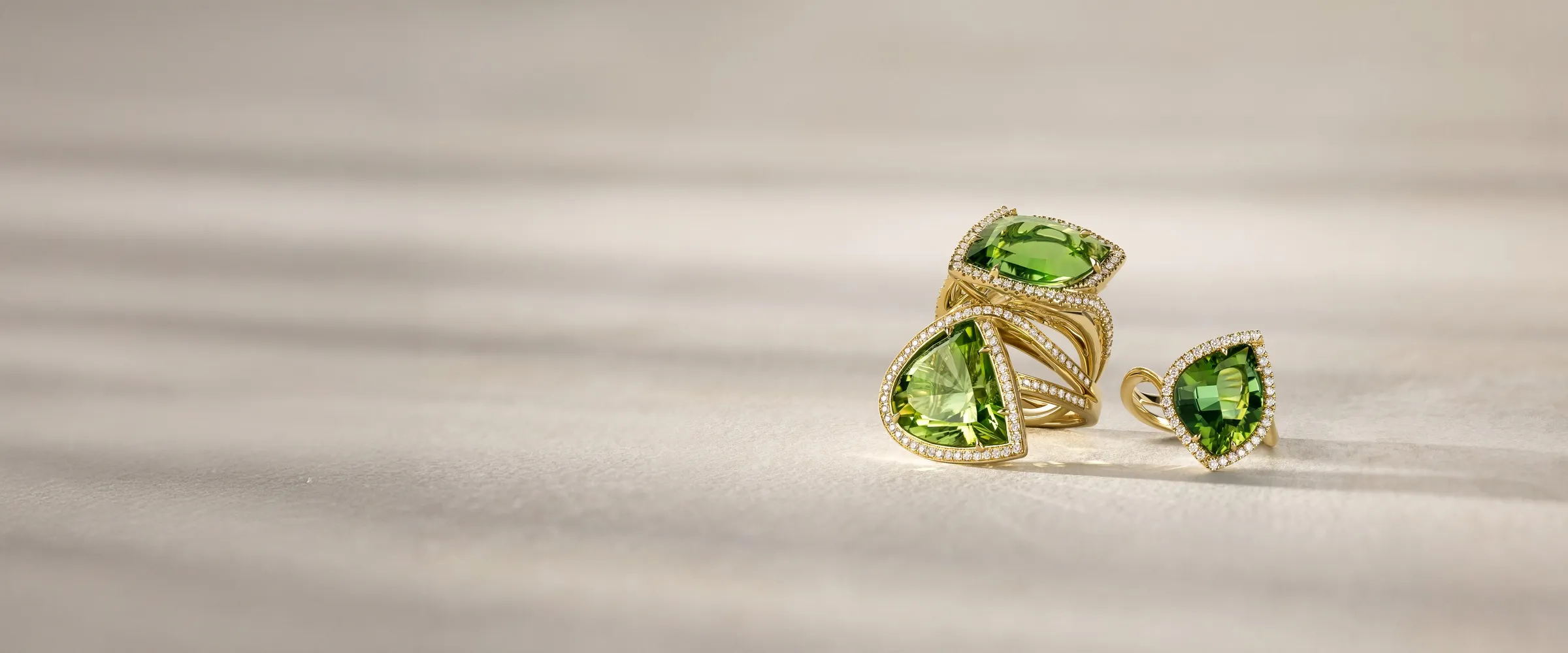 Three elegant gold rings featuring vibrant green gemstones, showcasing a luxurious jewelry collection.